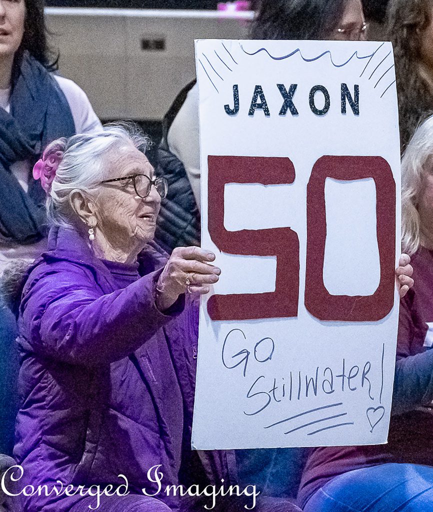 Elderly woman holding sign that says "Jaxon 50 Go Stillwater!"