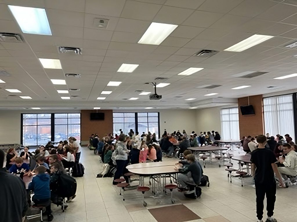 Students and staff sitting at tables in the school cafeteria.