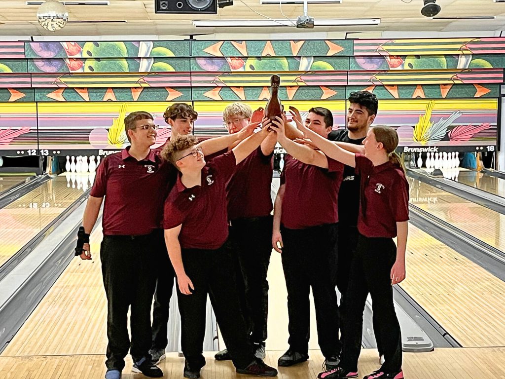 Bowling team holding up a pin.
