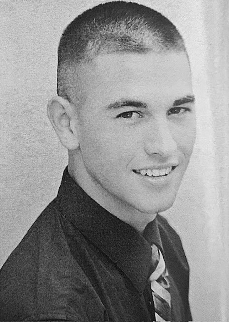 Man wearing a collared shirt and tie smiling.