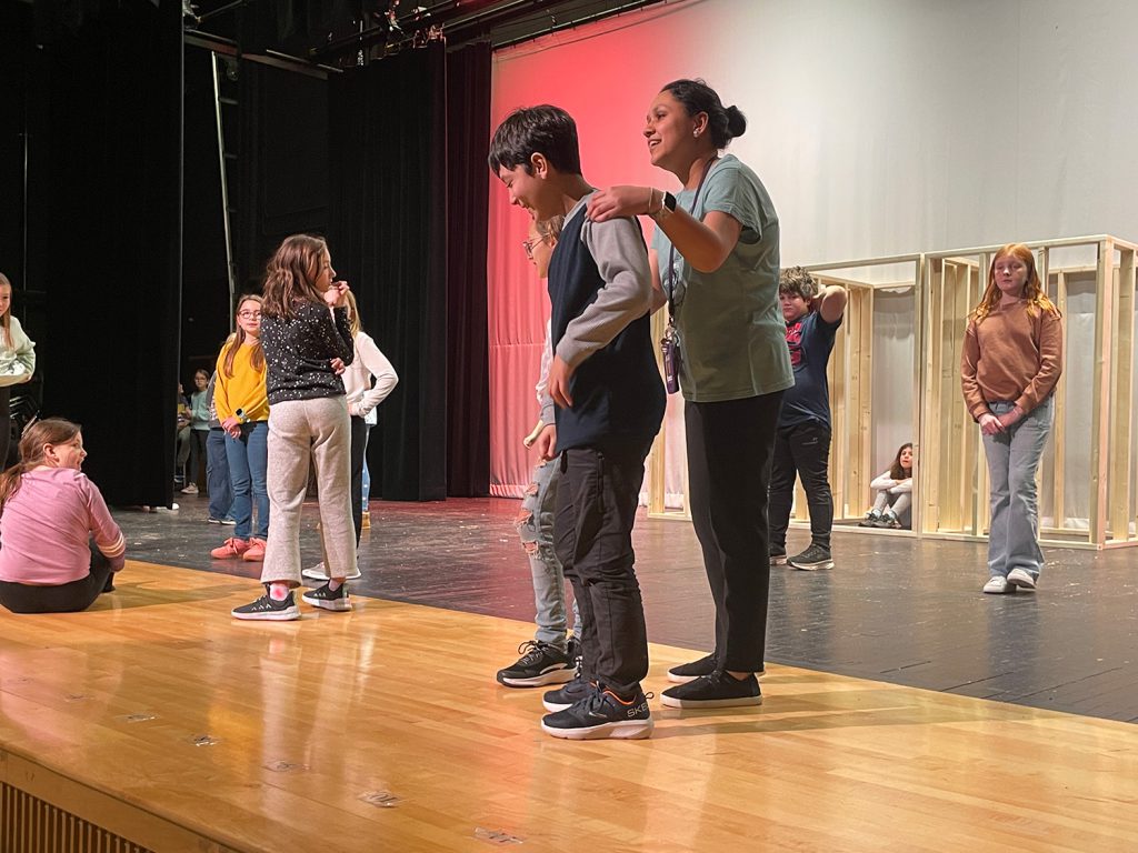 Teacher showing student where to stand on stage.