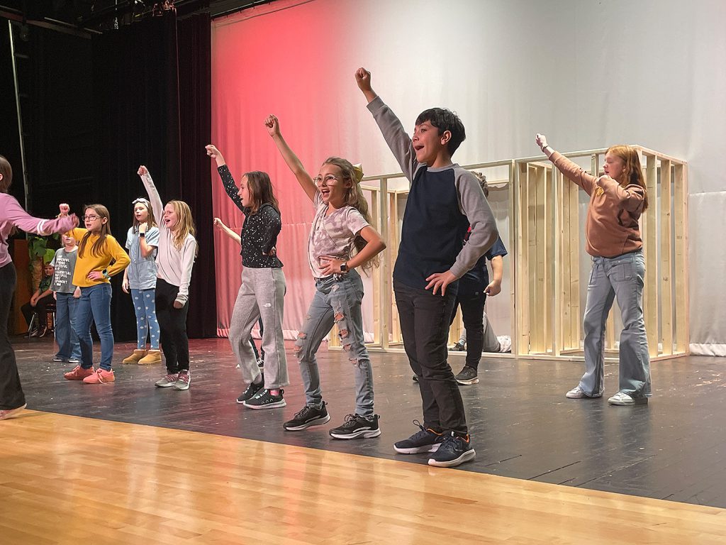 Students dancing on stage with one fist in the air.