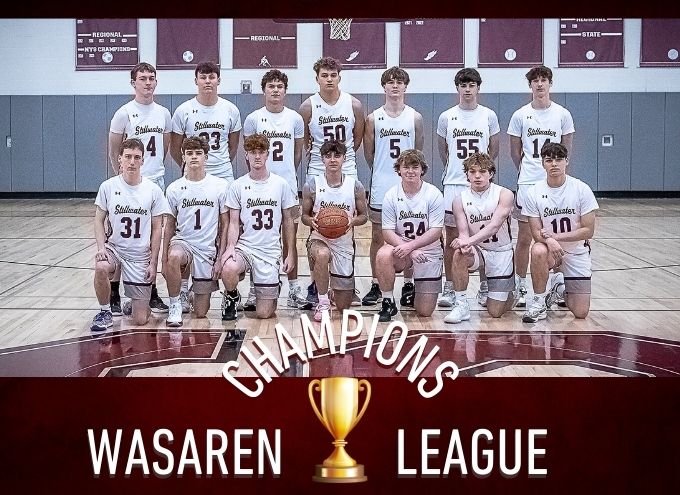 Group photo of boys varsity basketball team. A trophy is in front of the photo with "Wasaren League Champions" written.