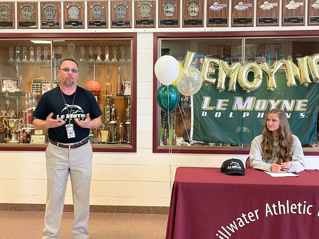 Coach speaking with a student sitting at a table to the left.