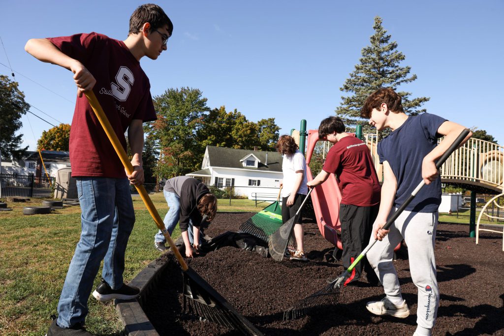 Students raking and adjusting a dirt pile.