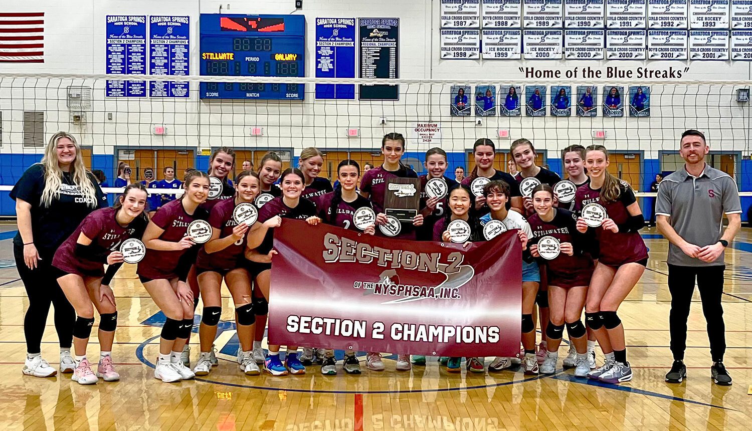 Group of athletes smiling with awards in hand and a banner stating "Section 2 Champions"