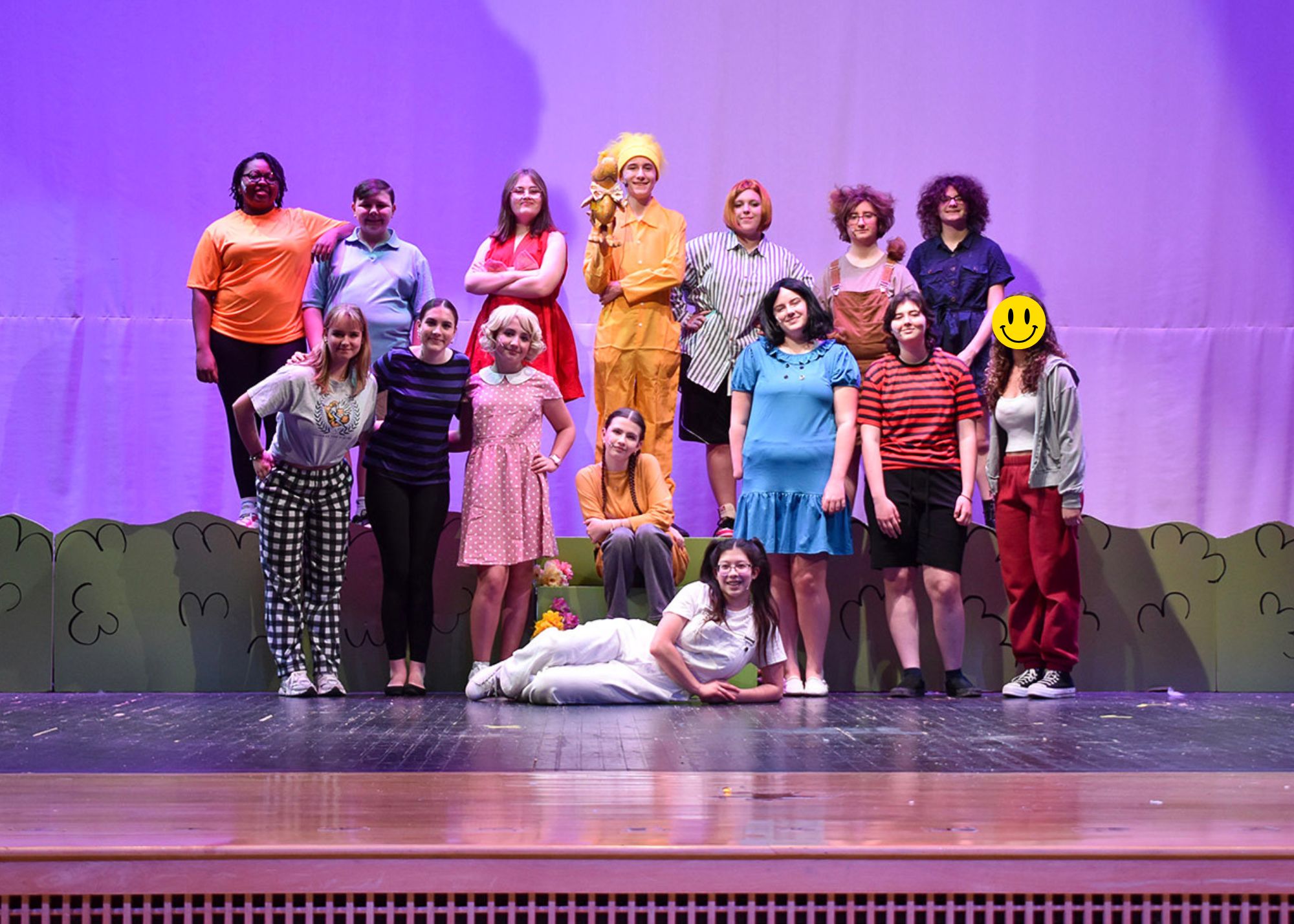 Drama club in attire smiling at the camera as a group.