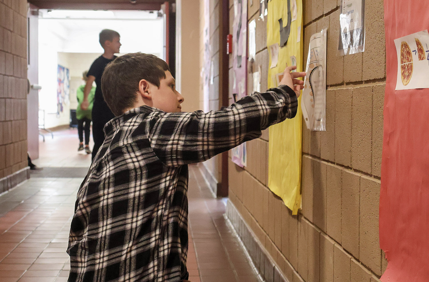 student peeling paper off of wall/