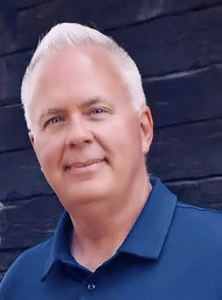 Headshot of Jay Peacock smiling with white hair and blue eyes.