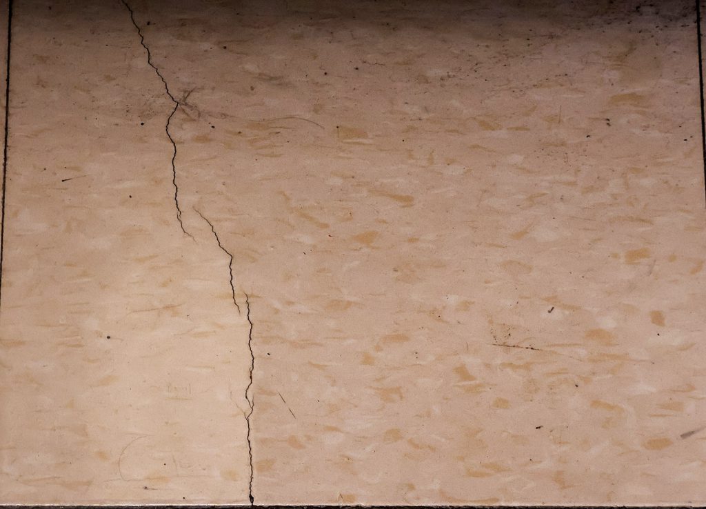 Up close photo of peach-colored cracked tile flooring.