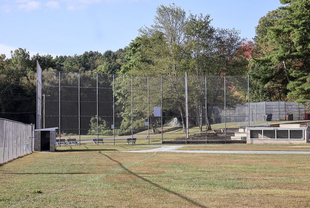 Baseball field with trees behind the metal fence.