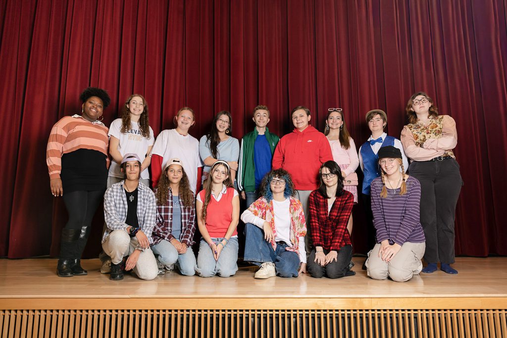 Several students standing together for a group photo on stage. All are smiling at the camera.