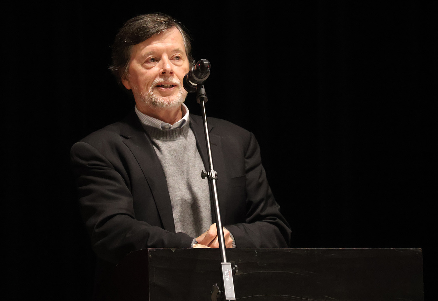 A man standing at a podium with a microphone, speaking.